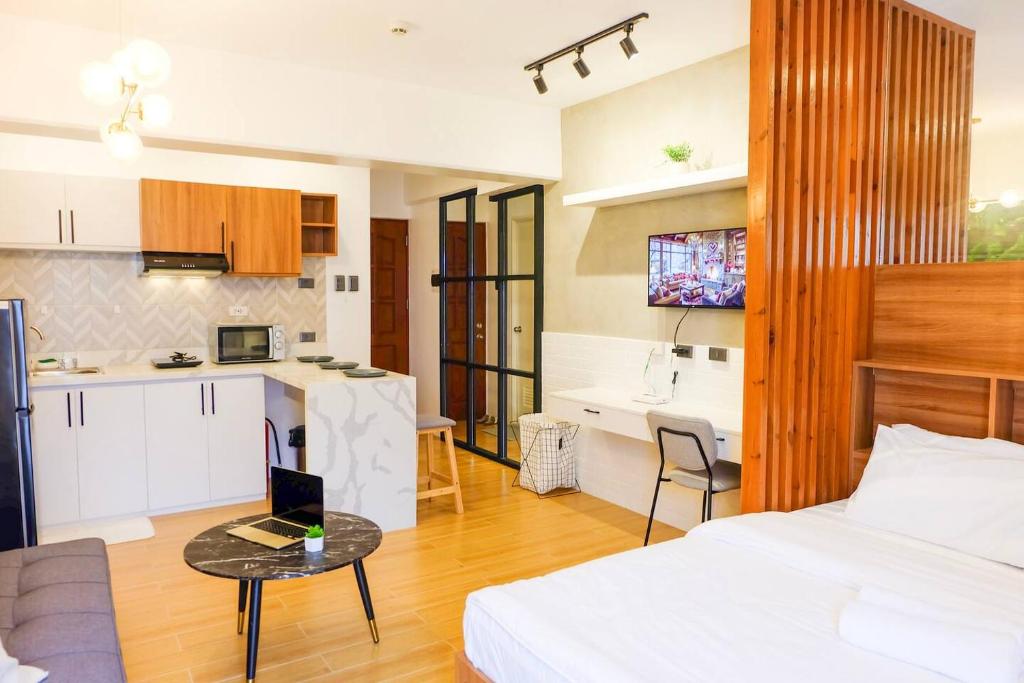 a bedroom with a bed and a table with a laptop at Chill Studio w Balcony & Free Pool Lapu-Lapu in Mactan Island