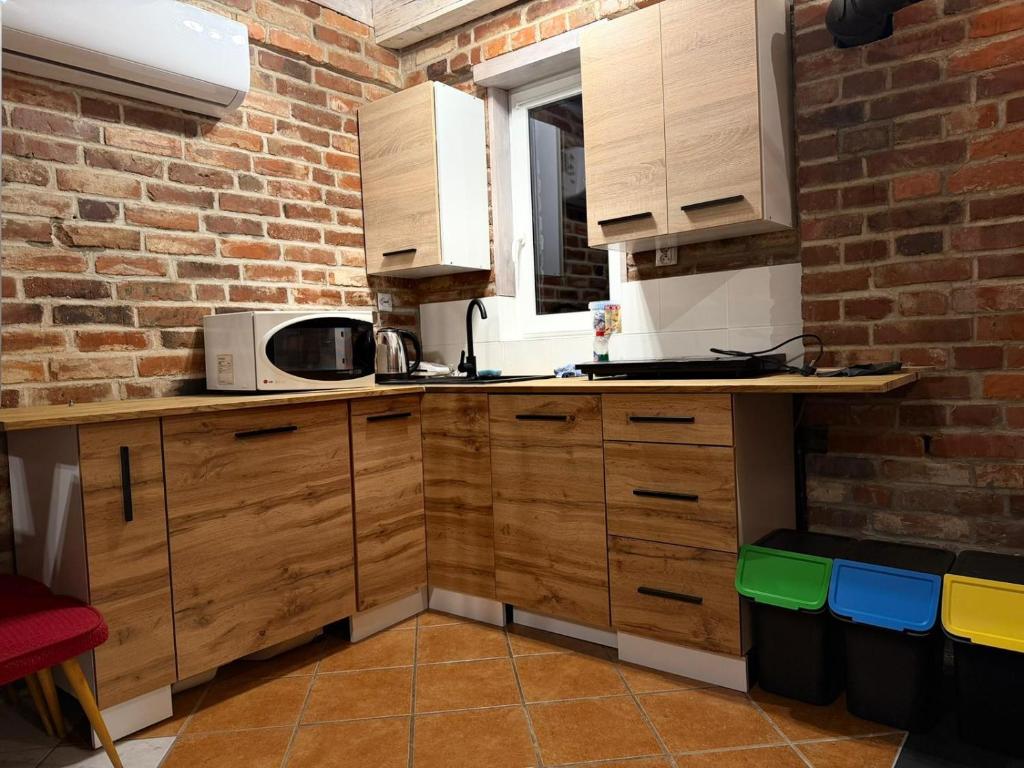 a kitchen with wooden cabinets and a brick wall at Na Pograniczu domek w górach in Lasowka