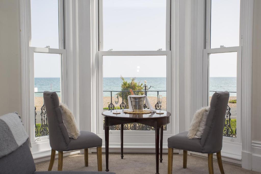 a dining room with a table and two chairs and windows at Seaways Apartment in Worthing