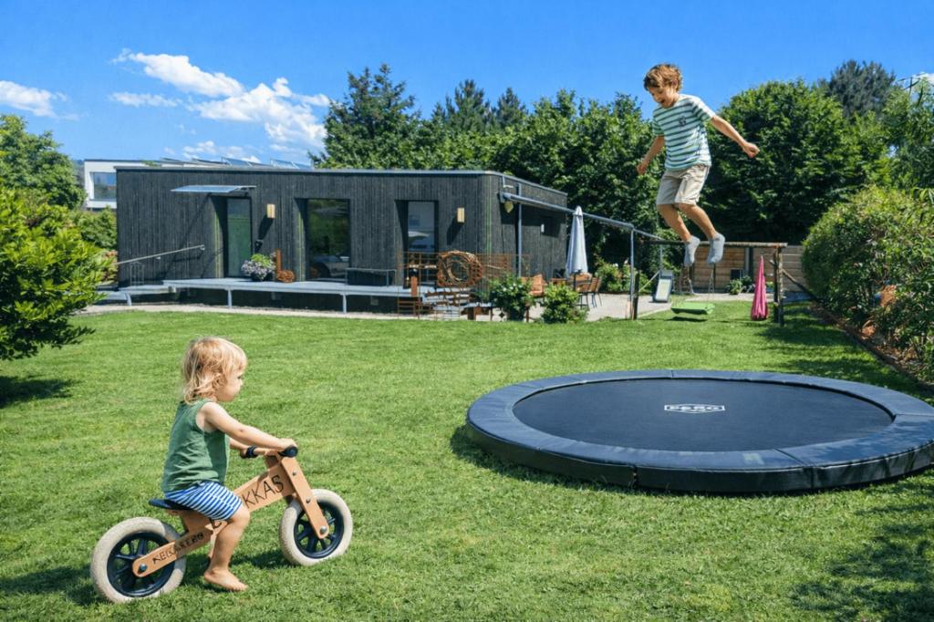two children playing on a trampoline in a yard at Ferienhaus Haus im Garten in Feldkirch