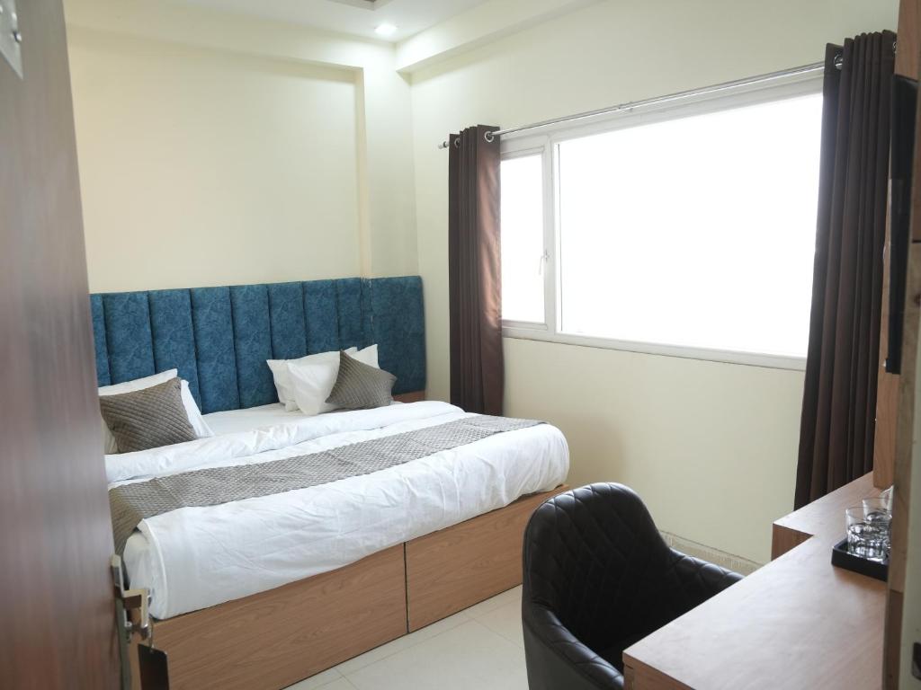 a bedroom with a bed with a blue headboard and a window at The RaaS Guestline in Noida