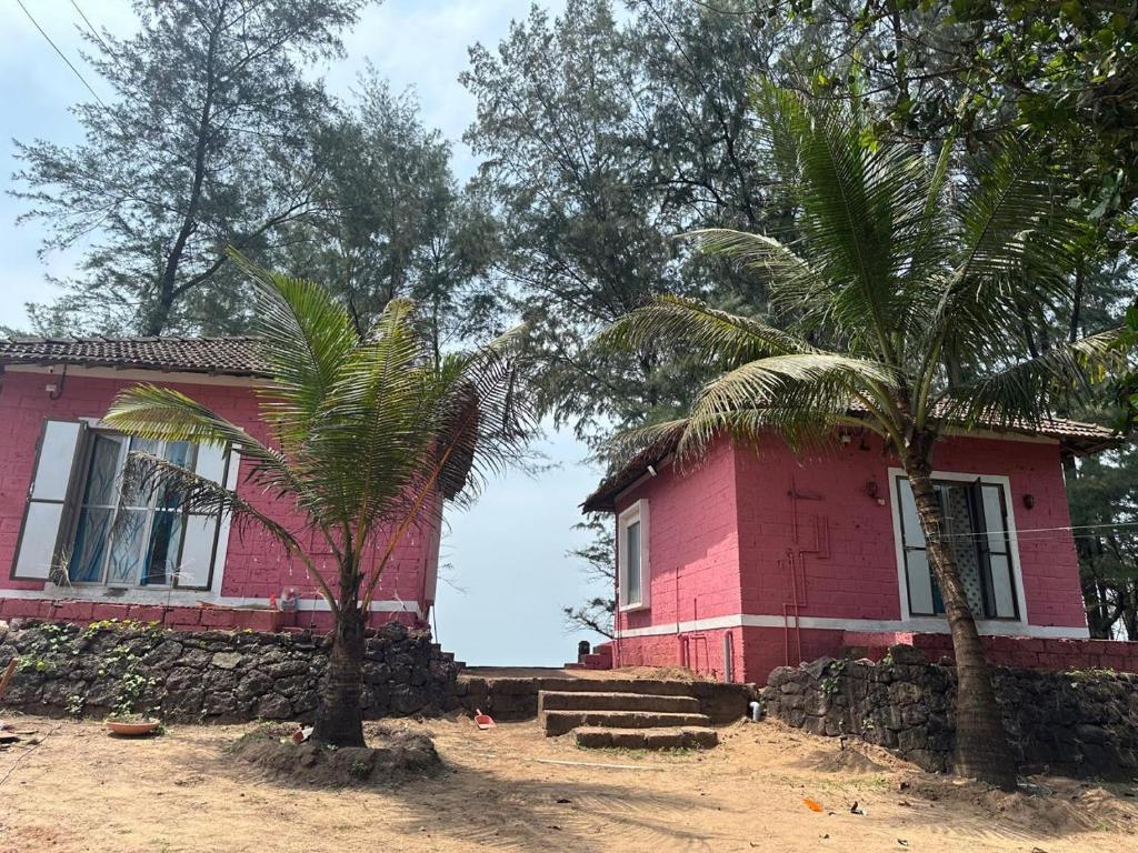 a pink house with two palm trees in front of it at The Redstones Resort in Malvan