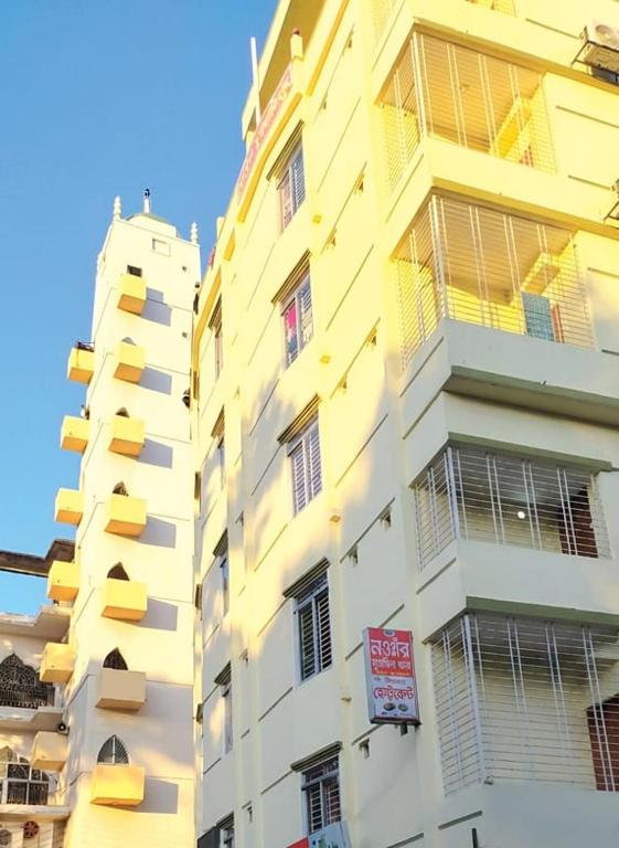a tall yellow building with a sign in front of it at Hotel SurmaLink in Sylhet