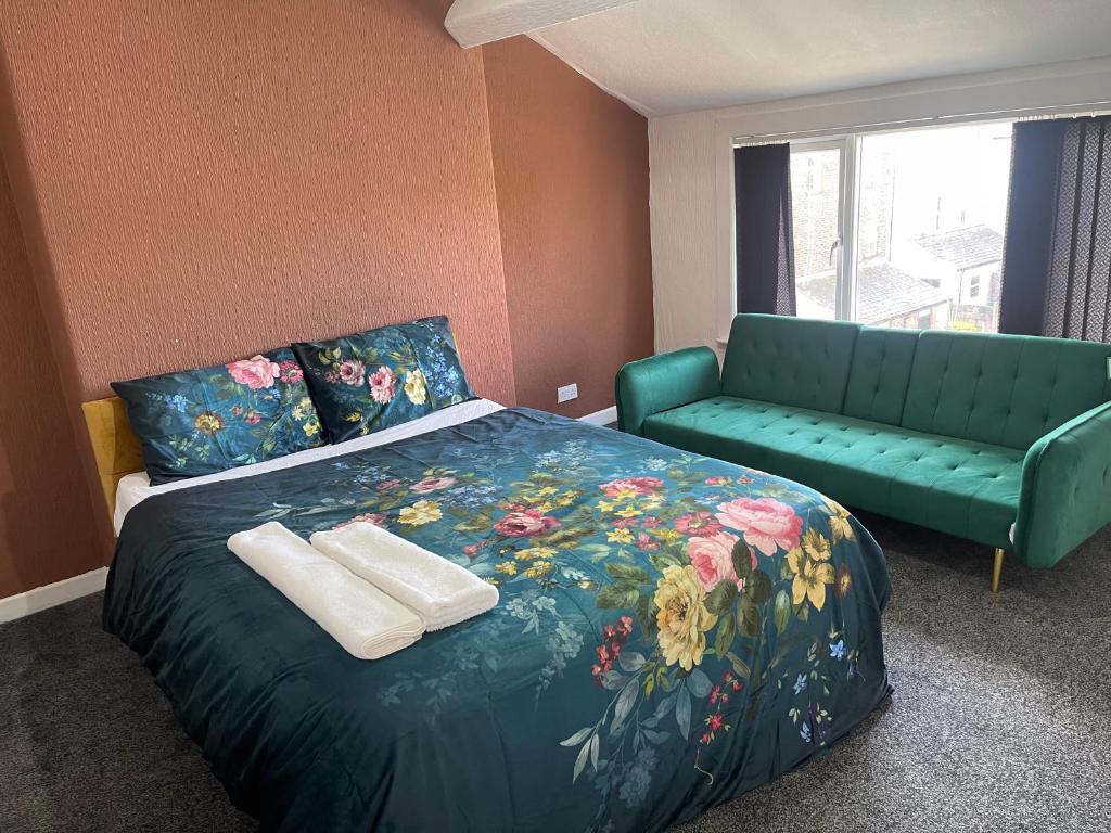 a bedroom with a bed and a green couch at Princess Shahzadi in Manchester