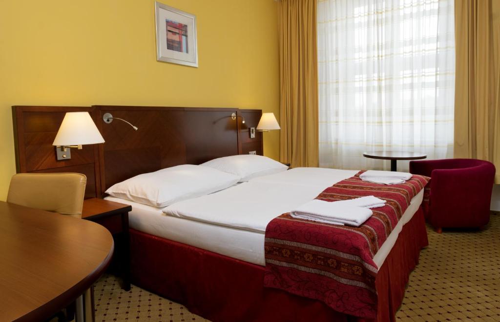 a hotel room with a large bed and a table at Hotel ZRUČ in Zruč nad Sázavou