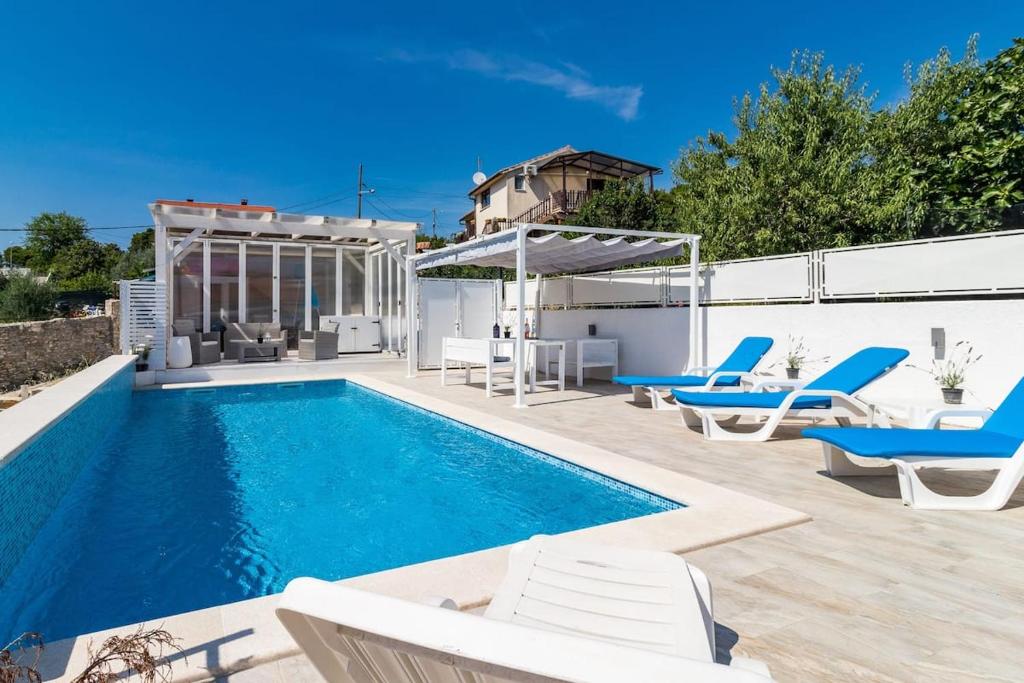 a swimming pool with lounge chairs and a house at Gradolina Apartment in Pula