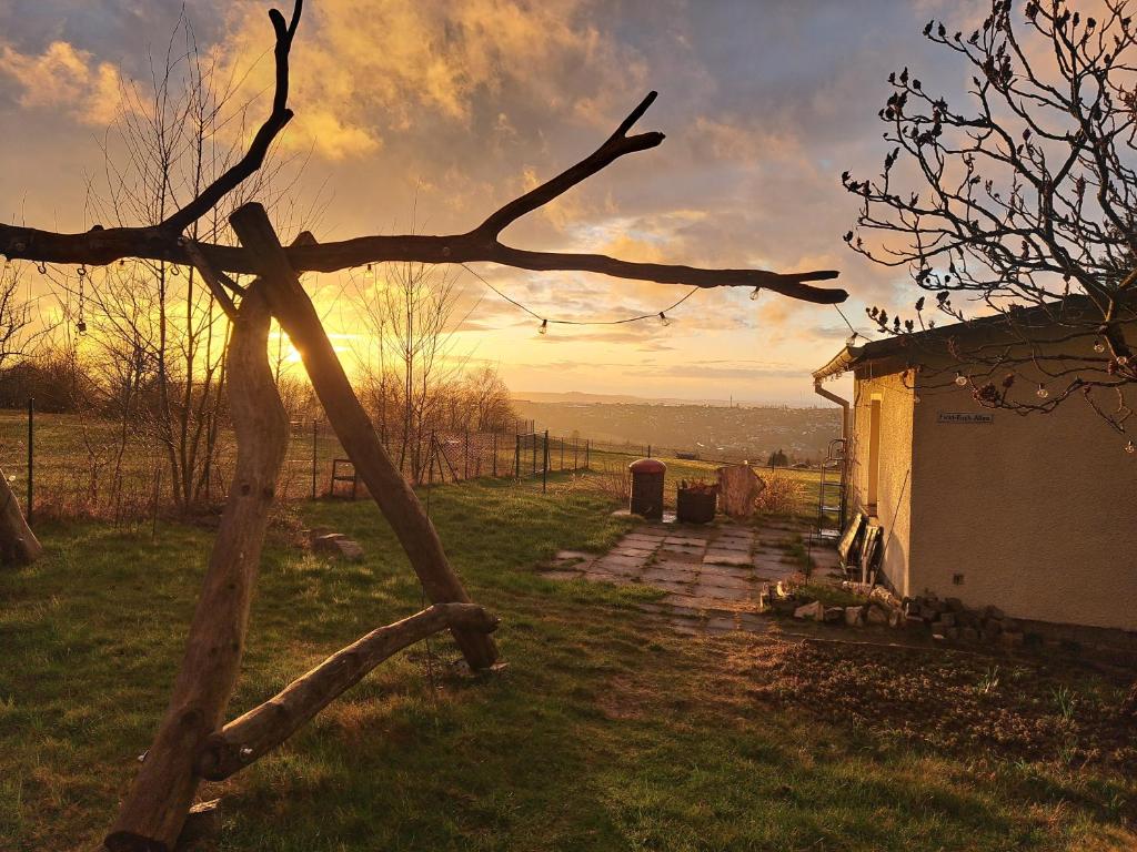 a tree branch in front of a house with the sunset at Goldener Blick in Stollberg