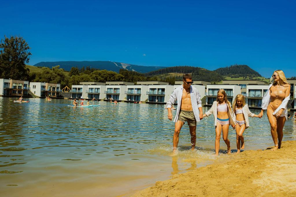 a group of people walking in the water on the beach at TILIA Resort in Dolný Kubín