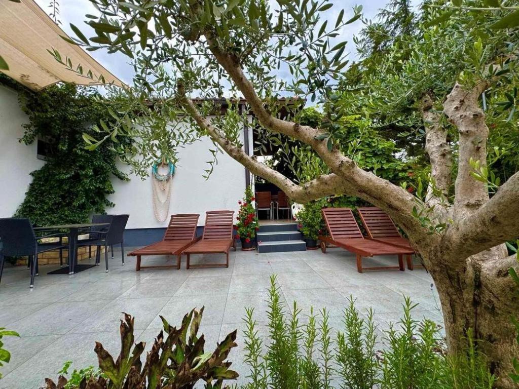 a patio with benches and a table and a tree at Apartment Ambretta in Savudrija
