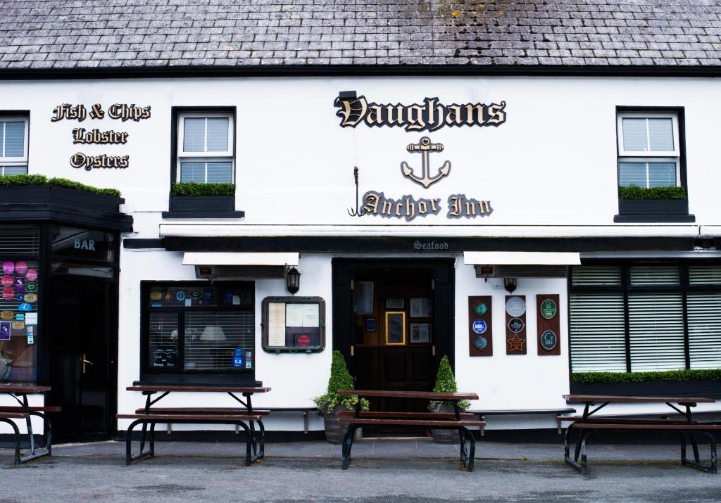 a white building with benches in front of it at Vaughans Anchor Inn in Liscannor