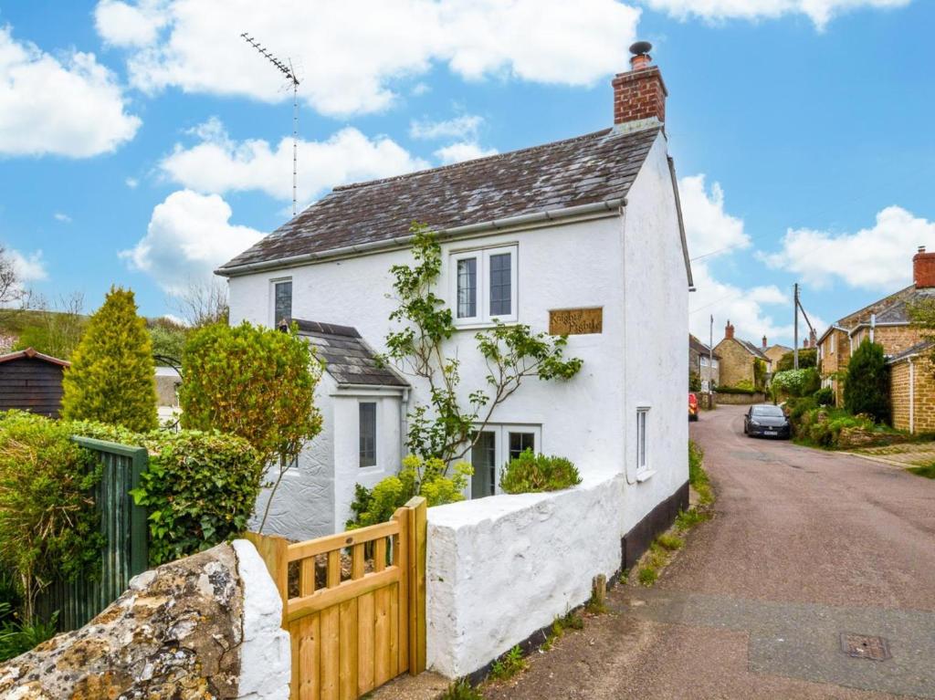 a white house with a fence on a street at 1 Bed in Bridport oc-dc085 in Loders