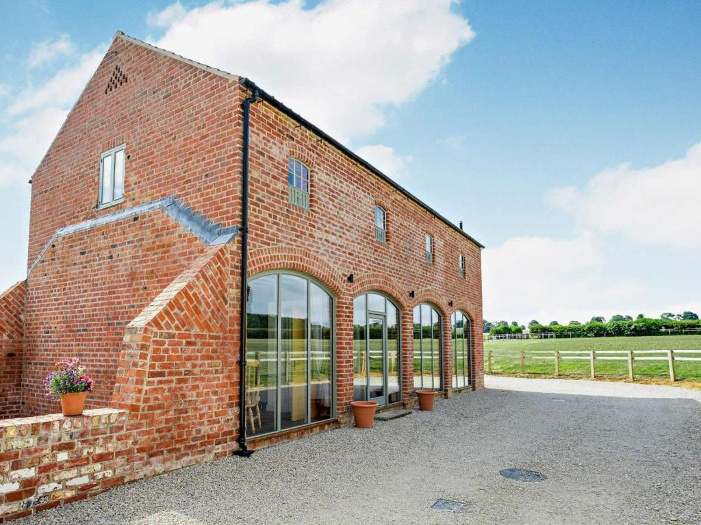 a brick building with large windows and a field at 3 Bed in Malton oc-75898 in Amotherby