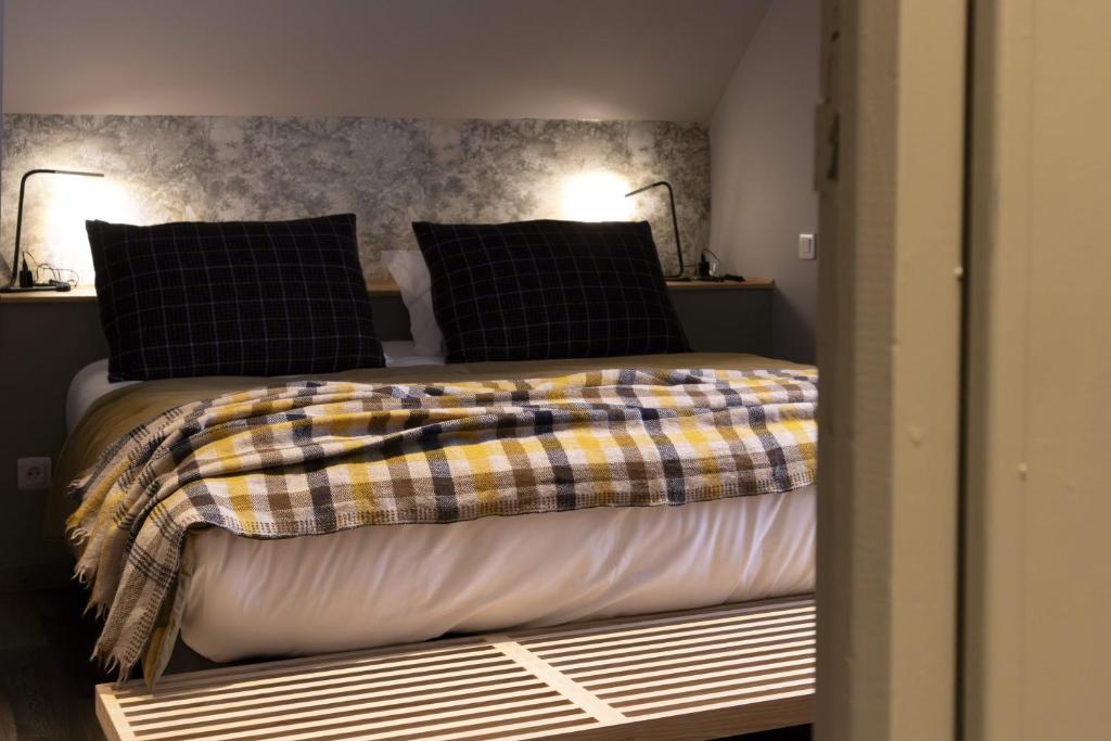 a bedroom with a bed with black and yellow blankets and pillows at Hotel Linette in Aumont-Aubrac