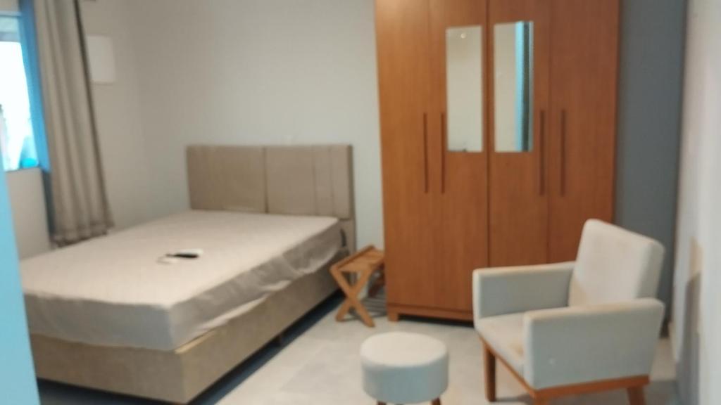 a bedroom with a bed and a chair and a cabinet at Maré Viva Hostel in Aracruz