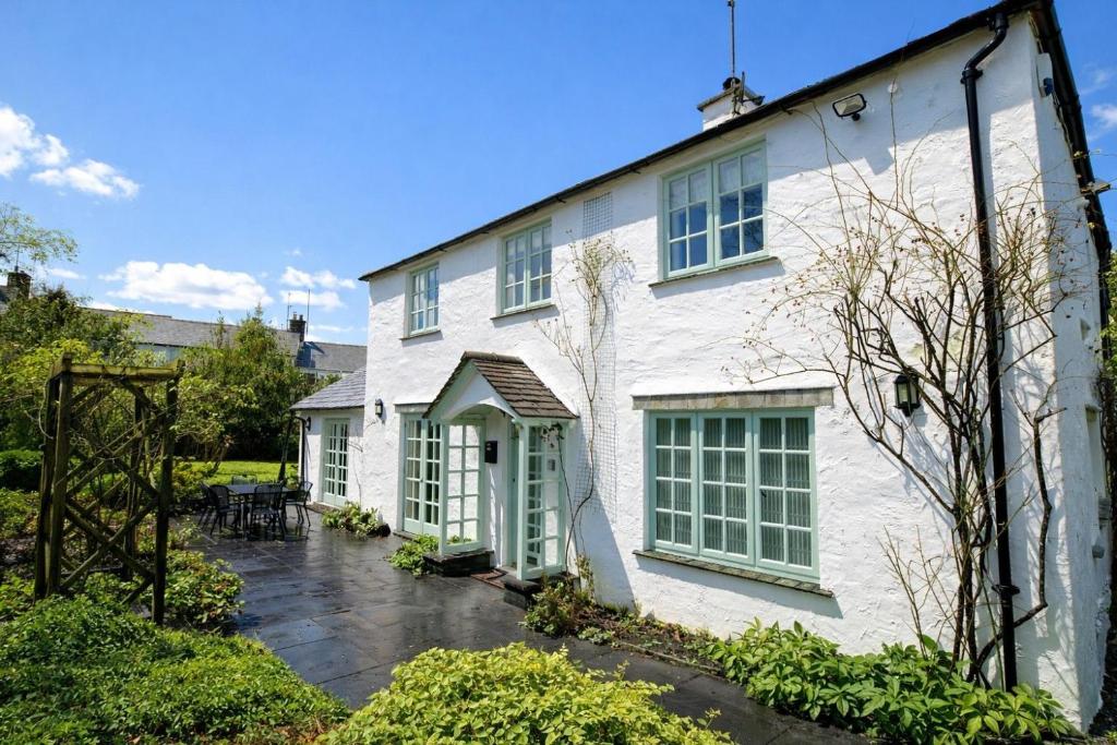 ein weißes Haus mit weißen Fenstern und einer Terrasse in der Unterkunft Brookside, Hawkshead with garden and parking in popular village in Hawkshead