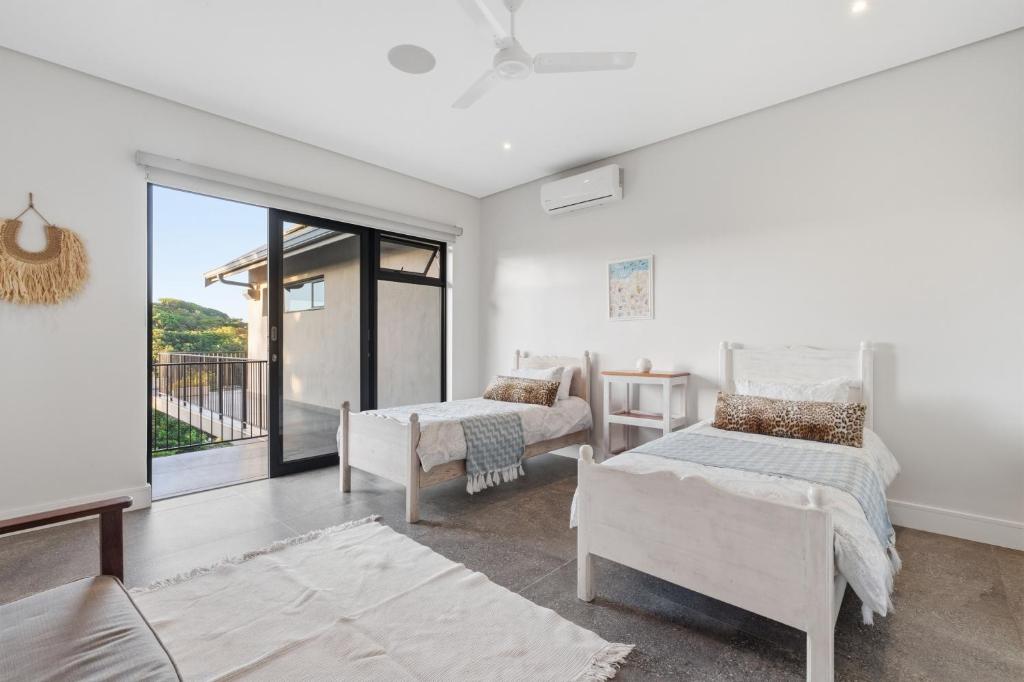 a bedroom with two beds and a balcony at Yellow-tail Room in Ballito