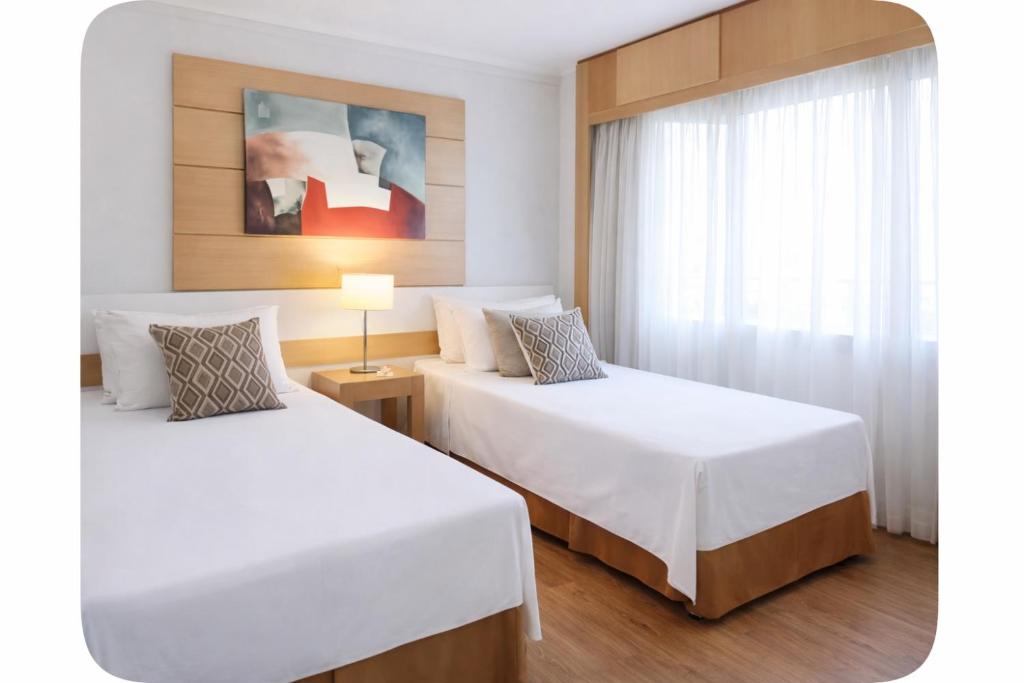 a bedroom with two beds and a window at Flat próximo ao Aeroporto Congonhas Piscina, Academia e Restaurante in São Paulo