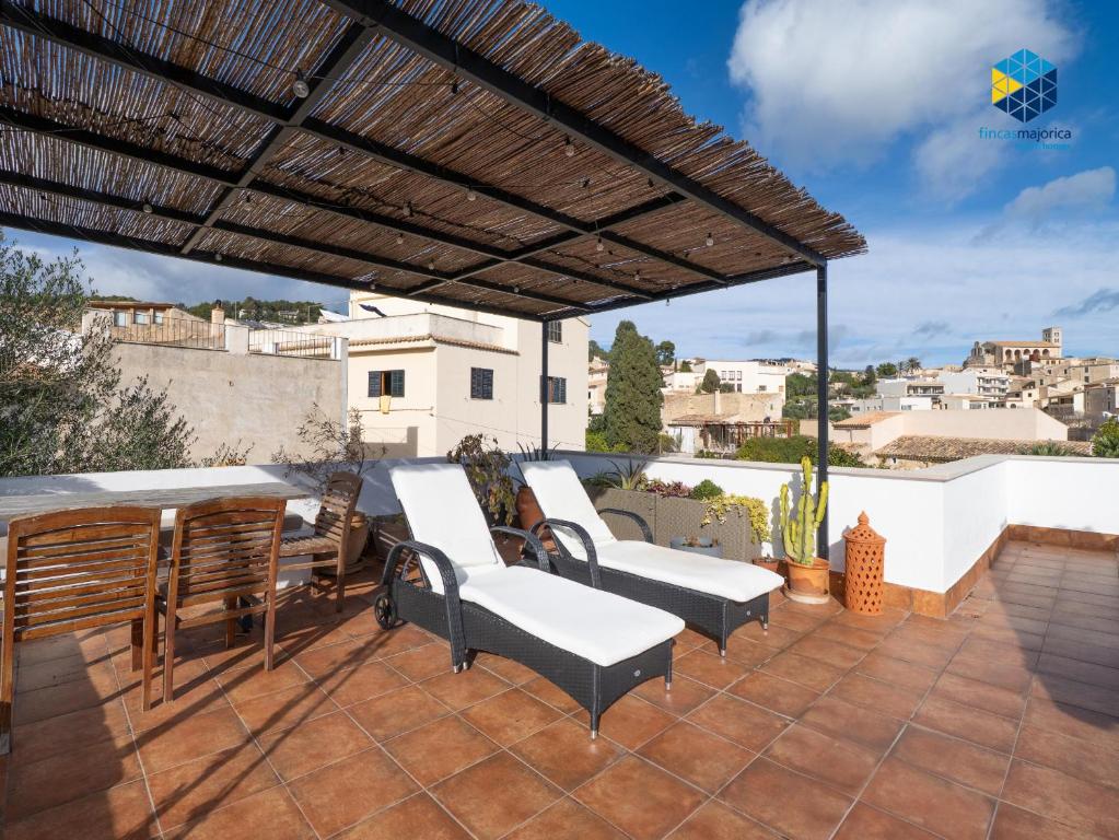 a patio with white chairs and a roof at La Caseta de Lola in El Port de la Selva