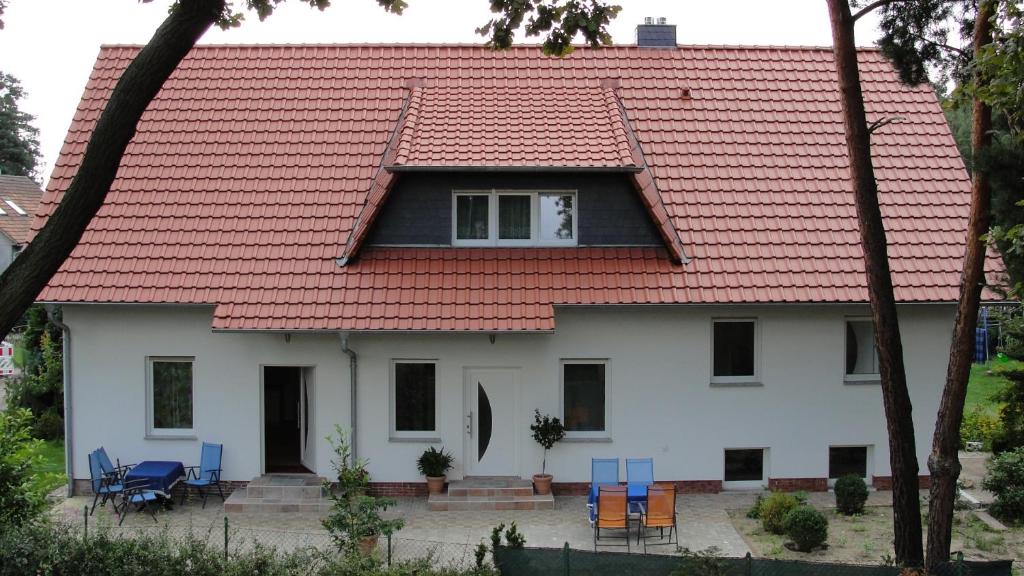 a white house with a red roof and blue chairs at Ferienreihenhäuser Roswitha in Frauenberg