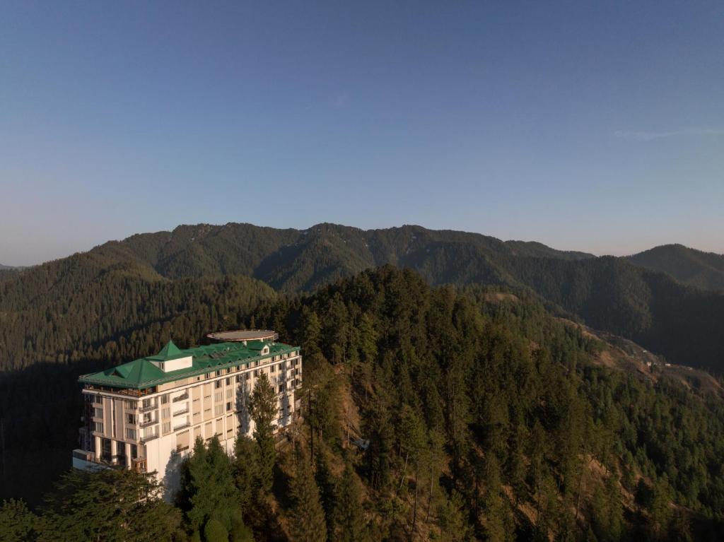 a building on the side of a mountain with trees at The Greenberry Mountain Resort Narkanda in Nārkanda
