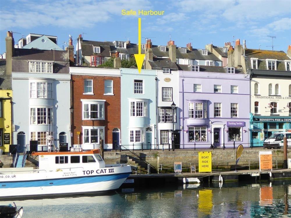 a boat is docked next to a group of buildings at Safe Harbour in Weymouth