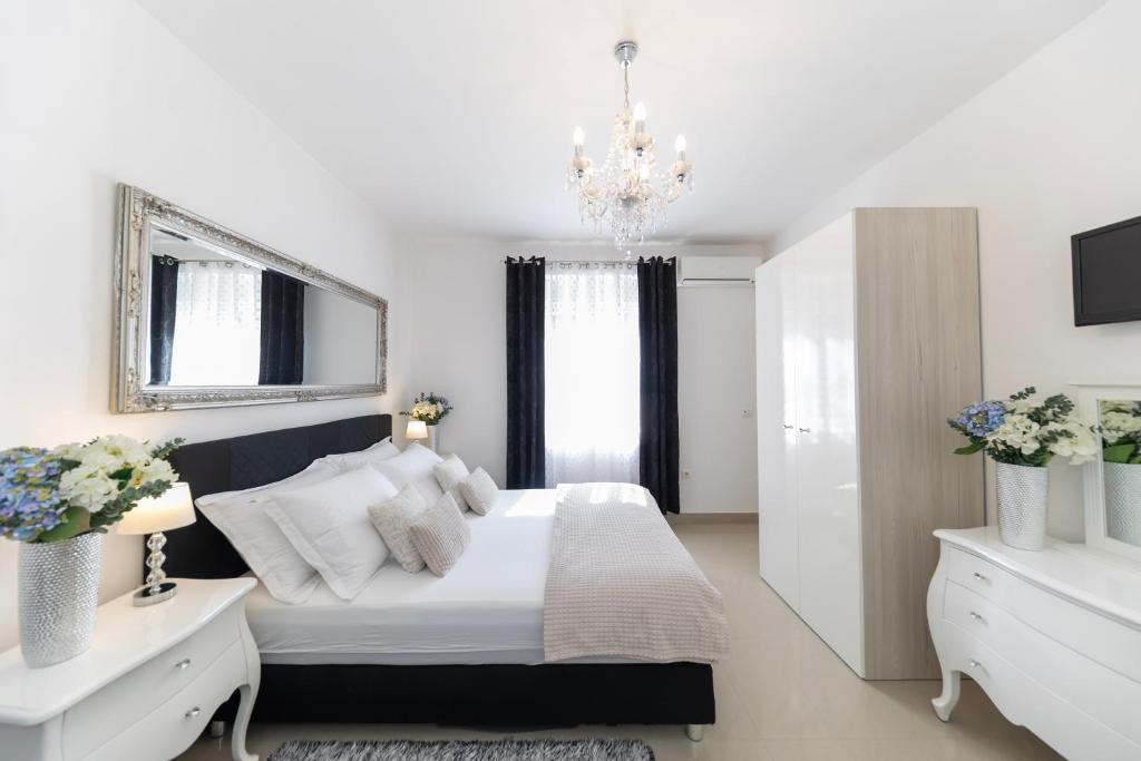 a white bedroom with a bed and a chandelier at Central Square Luxury Boutique in Zadar