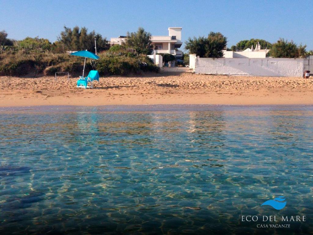 a beach with a chair and an umbrella and the water at Eco del Mare in Savelletri di Fasano