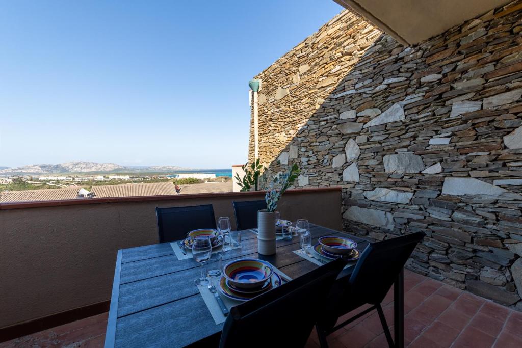 a table and chairs on a balcony with a stone wall at L11 Terrazza Maestrale in Stintino