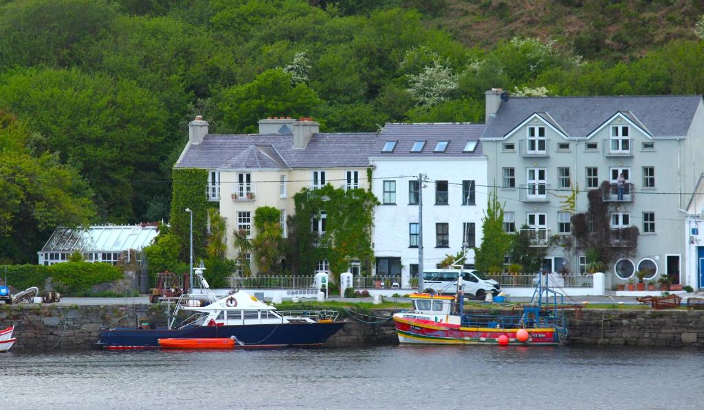 a large white house with boats in the water at The Quay House in Clifden
