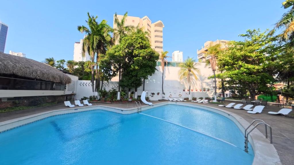 a large swimming pool with lounge chairs and palm trees at Hotel Bahia Cartagena in Cartagena de Indias