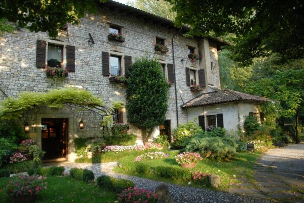 a large stone house with a garden in front of it at Hotel L'Ultimo Mulino in Bannia