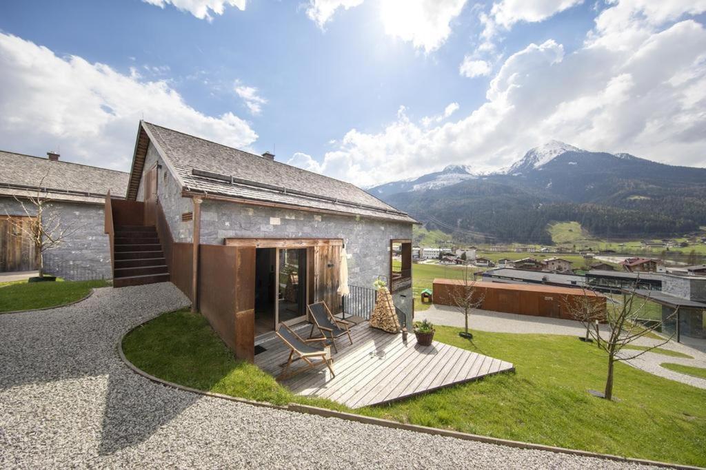 a stone house with a patio and mountains in the background at Smaragdresort Chalet Bergblick in Bramberg am Wildkogel