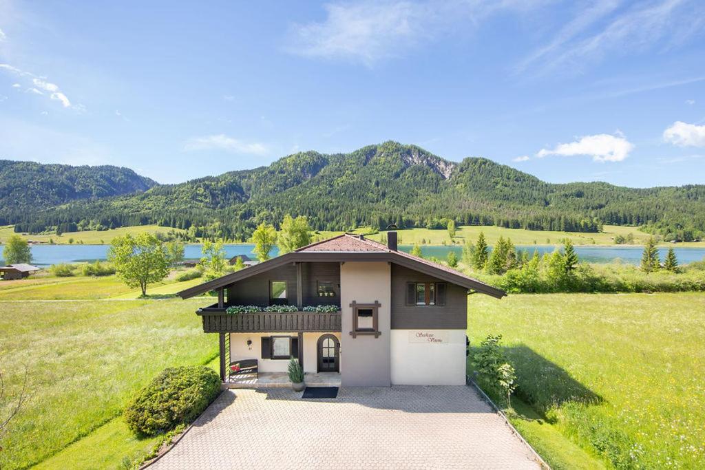 a house in a field with mountains in the background at Seehaus Verena in Weissensee