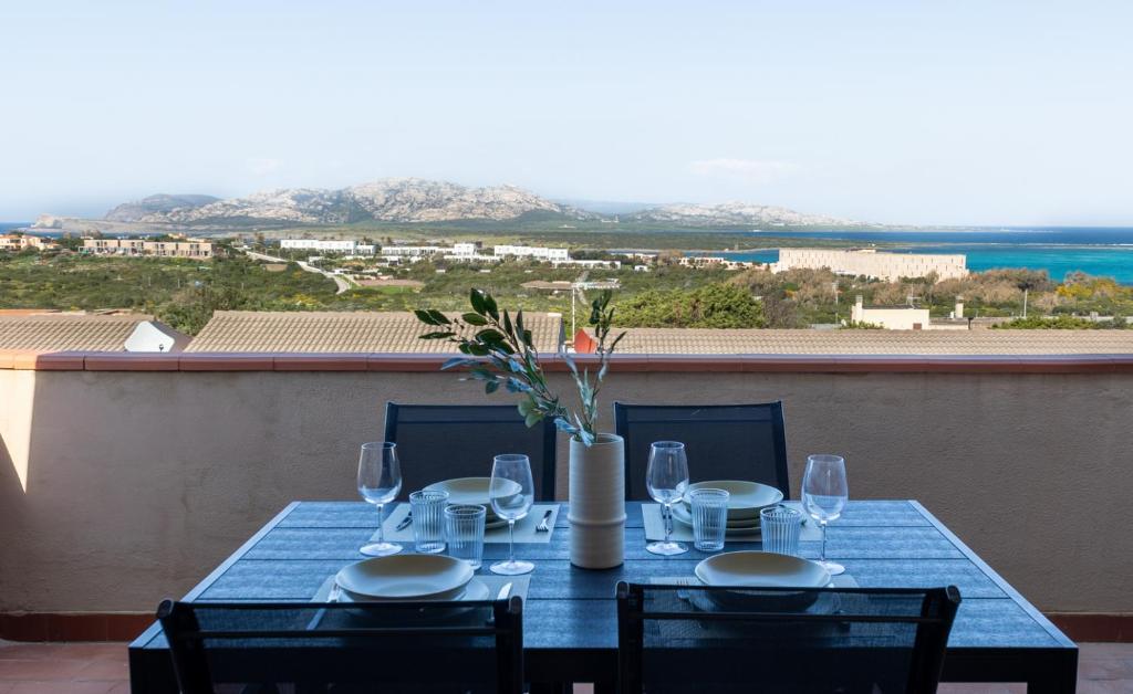 a blue table with glasses and a vase with flowers at L10 Terrazza Ponente A breathtaking view in Stintino