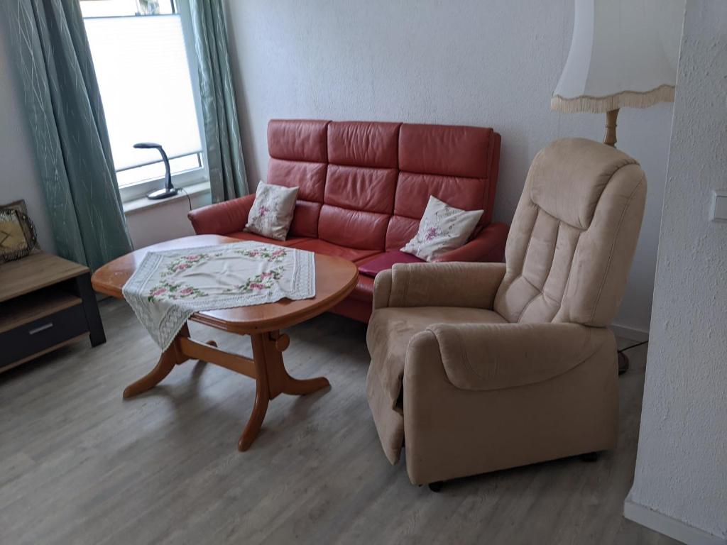 a living room with a red couch and a chair at Auszeit im Vorharz in Wegeleben