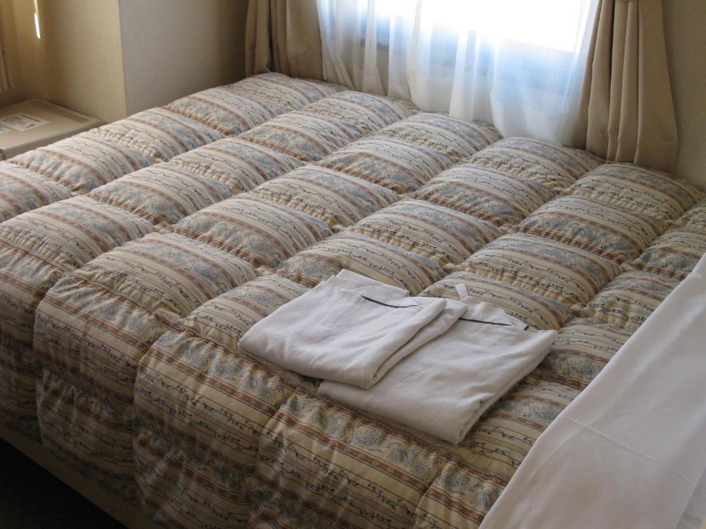 Postel nebo postele na pokoji v ubytování Mito Riverside Hotel