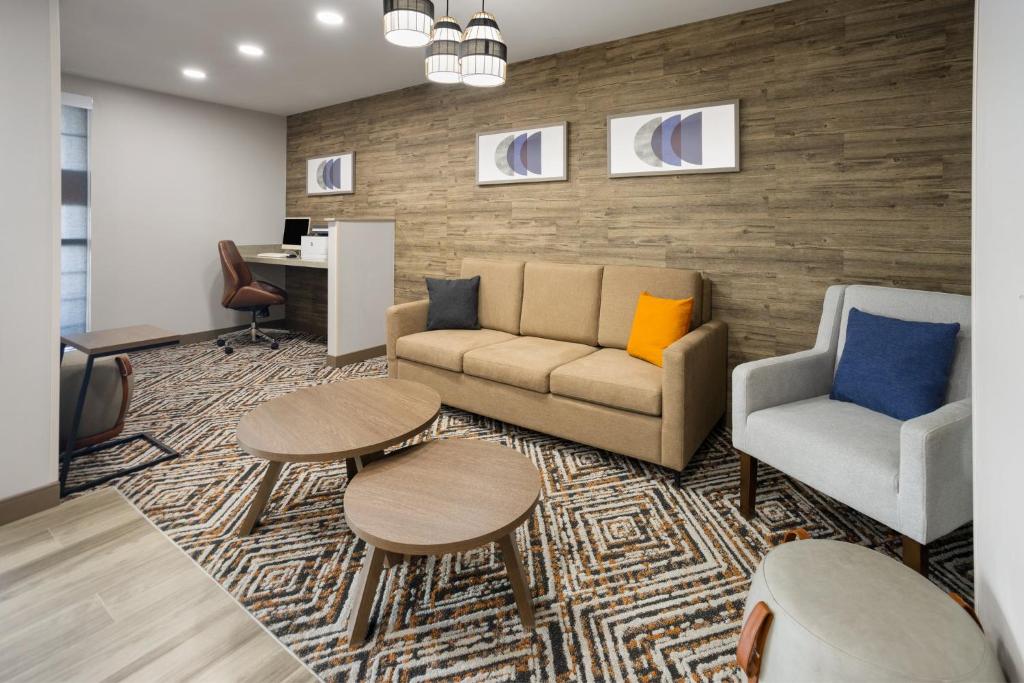 a living room with a couch and two chairs and a desk at Candlewood Williamsport by IHG in Williamsport