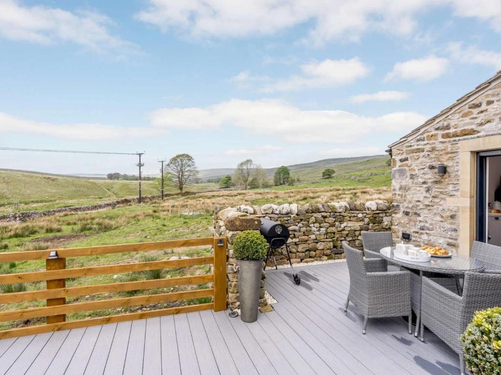 a deck with a table and chairs and a stone wall at 2 Bed in Skipton oc-82602 in Buckden