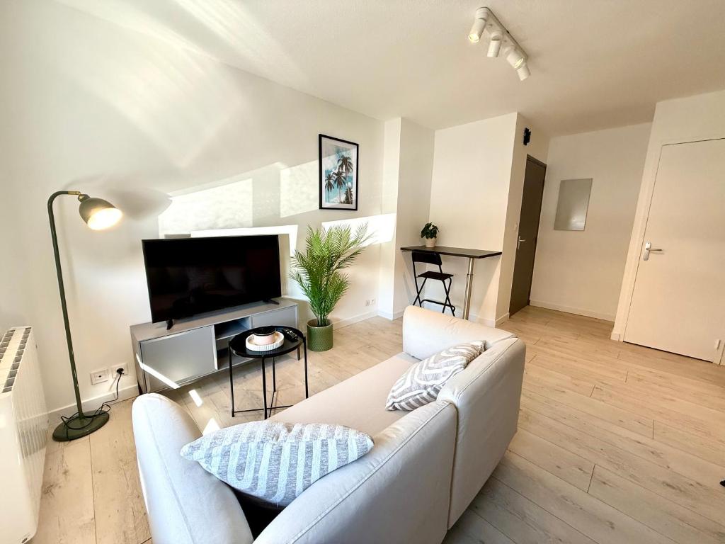 a living room with a white couch and a flat screen tv at Appartement calme parking in Le Monastère