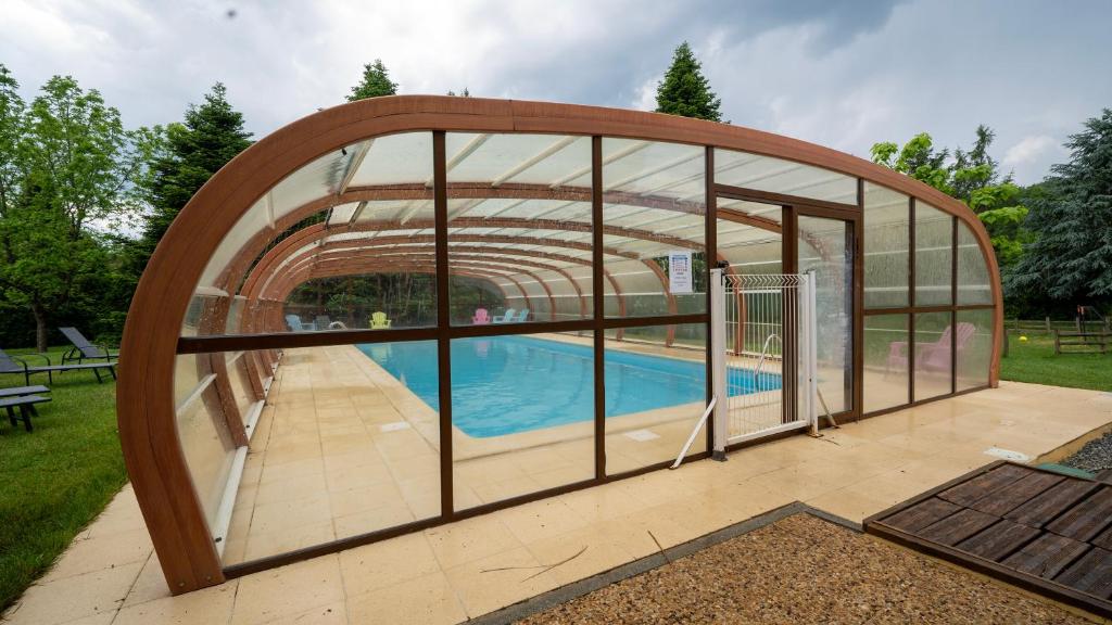 a pool house with a glass door and a swimming pool at Le Village des Monédières in Chamberet