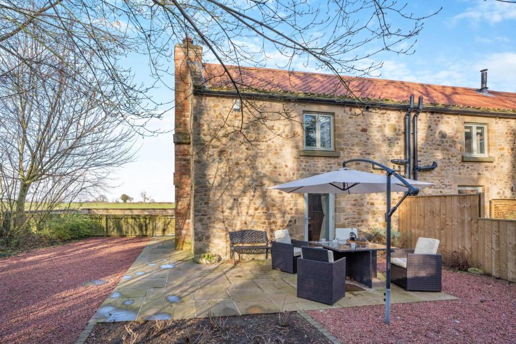 a brick house with an umbrella and a table and chairs at 3 Bed in Crakehall oc-m30356 in Crakehall
