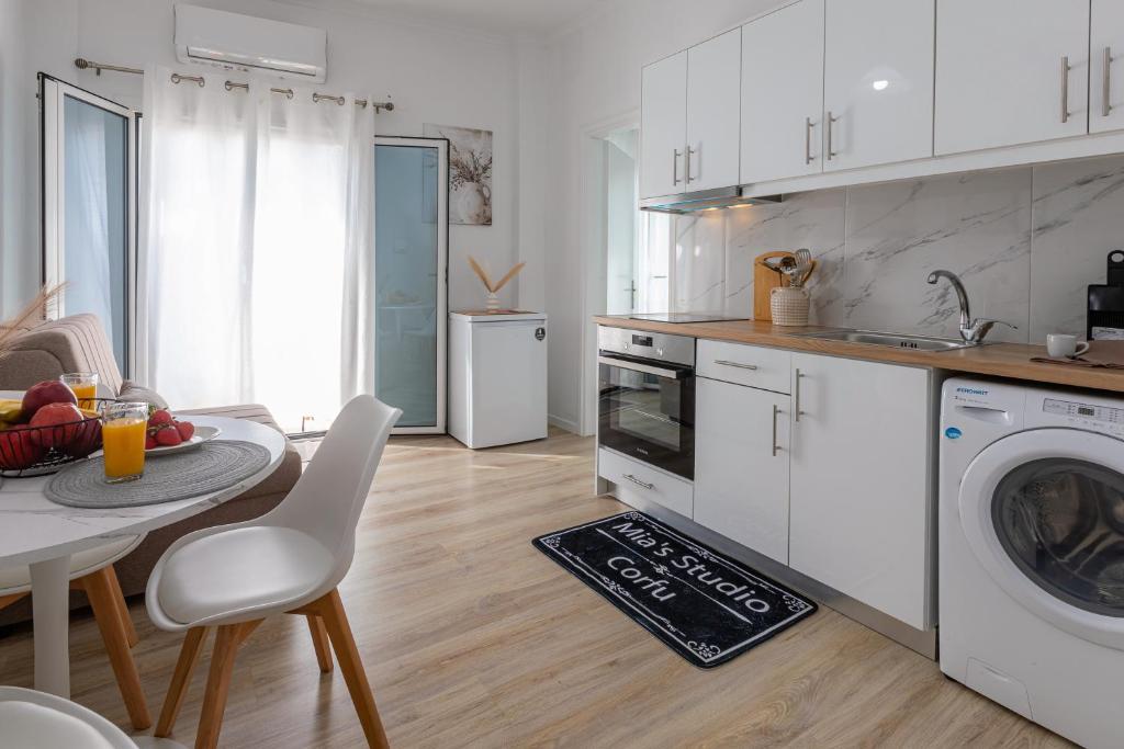 a kitchen with white cabinets and a table with a bowl of fruit at Mia's Studio in Corfu