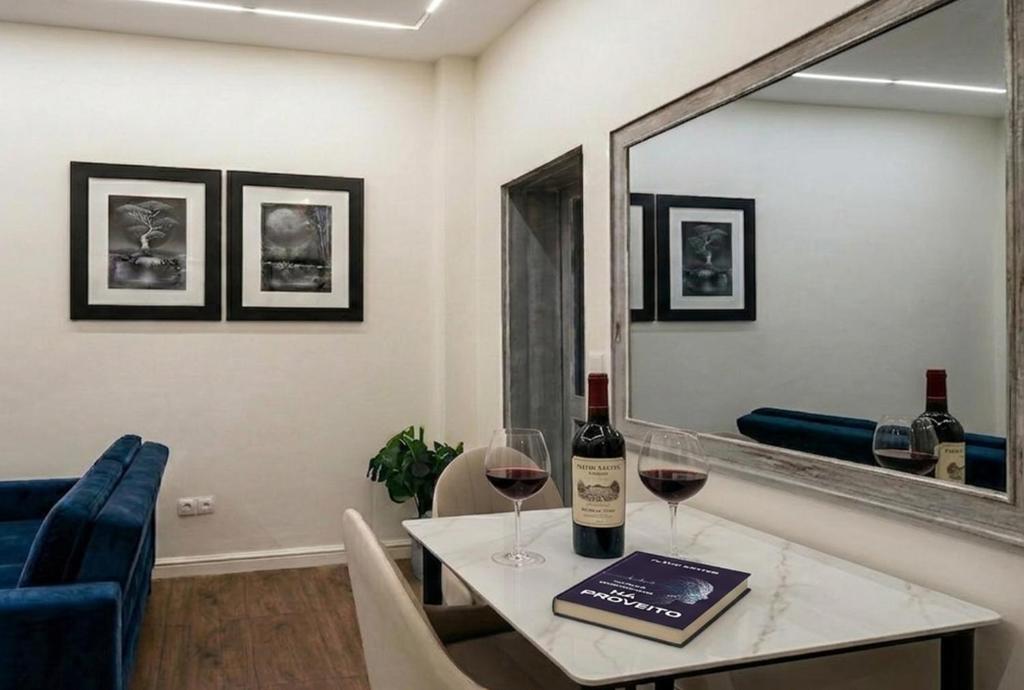 a table with two glasses of wine and a mirror at Mutamba Prime Stay in Luanda