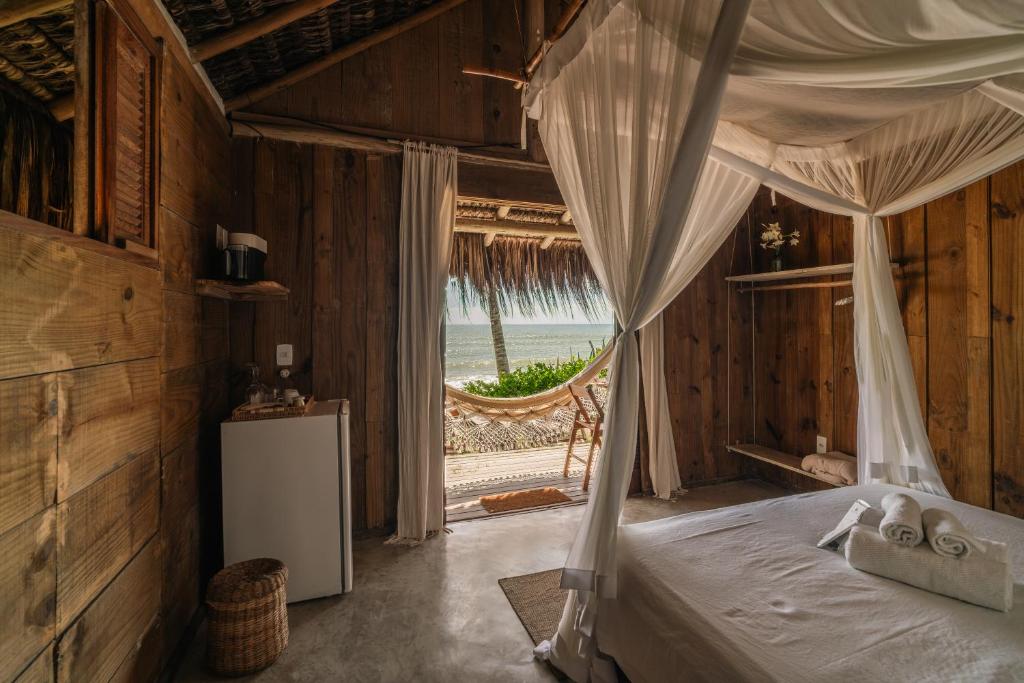 a bedroom with a canopy bed with a view of the ocean at Vila Fruta Pão in Caraíva
