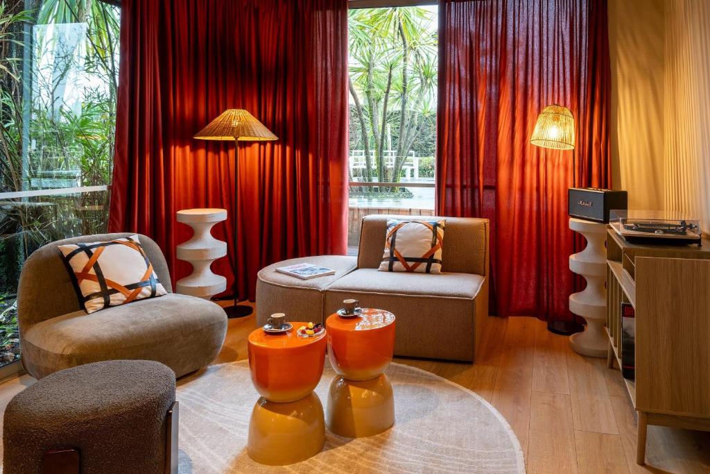 a living room with two chairs and red curtains at Best Western Hôtel du Phare in Mérignac