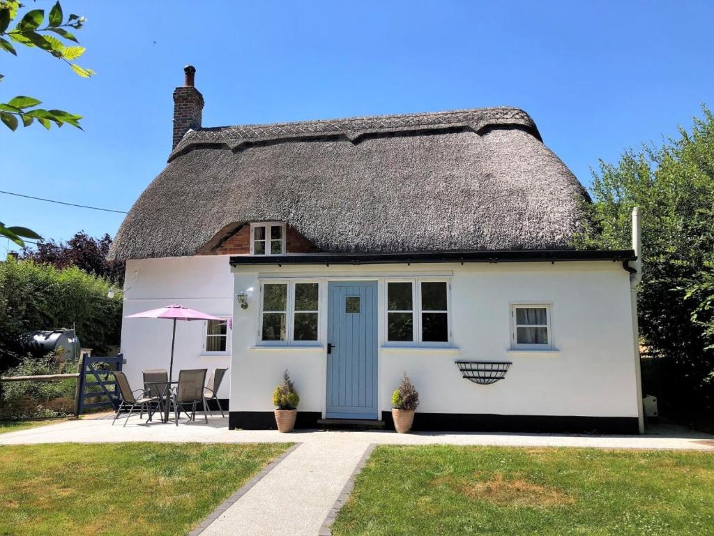 a cottage with a thatched roof with a patio at 2 Bed in Romsey oc-thatc in Newtown
