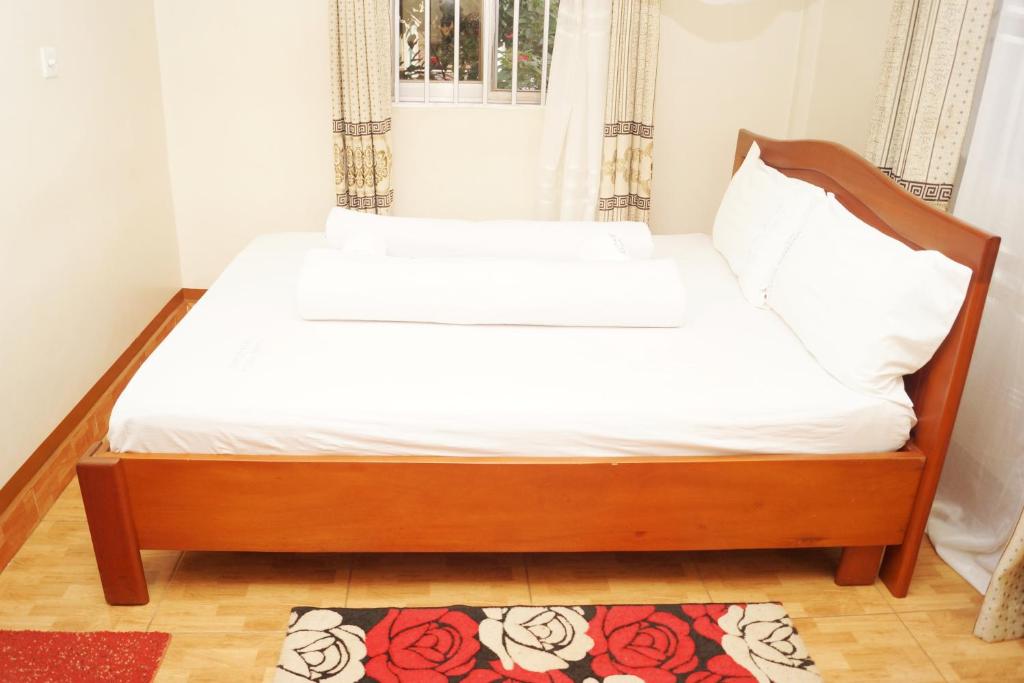 a bed with a wooden frame and white sheets at Vision Hotel Kampala in Kampala