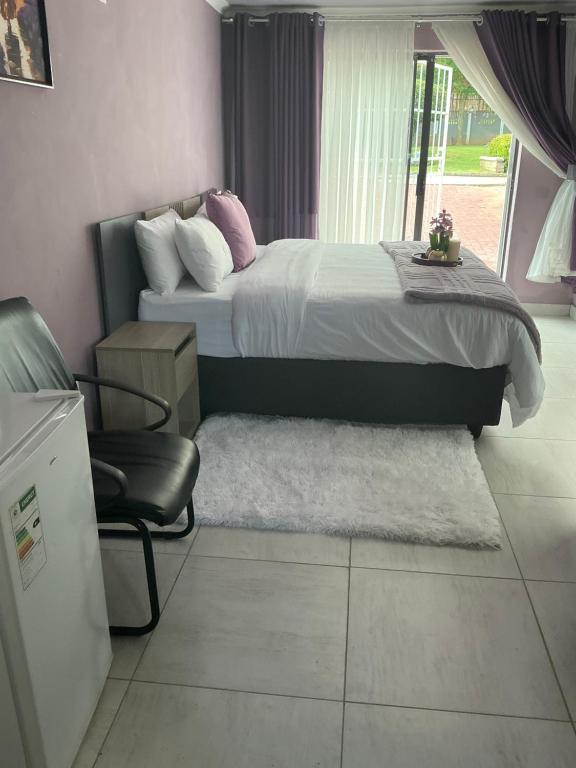 a bedroom with a bed and a chair and a window at Paradise Guest House in Roodepoort