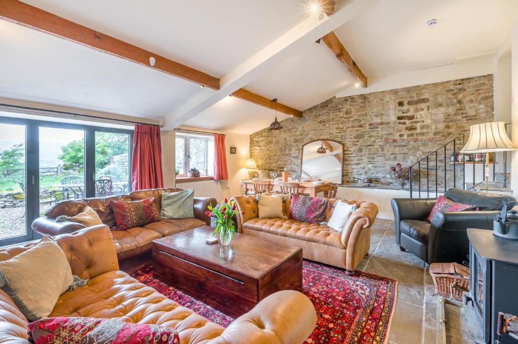 a living room with leather furniture and a stone wall at 1 Bed in Middleham oc-c30871 in Gammersgill