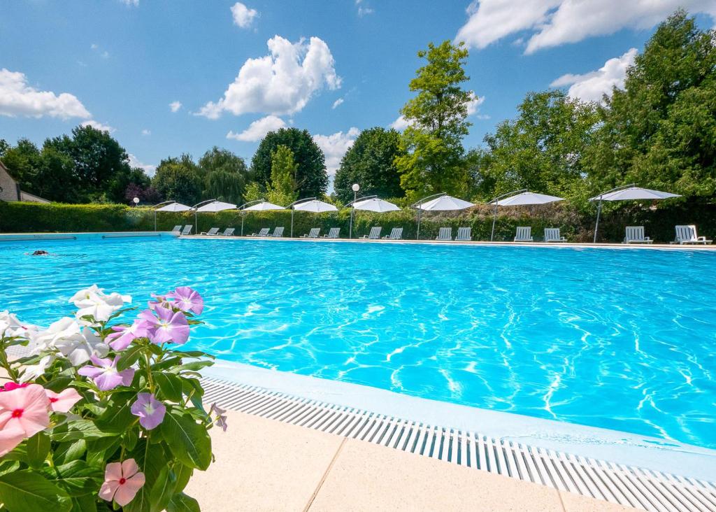 a swimming pool with blue water and white umbrellas at Glamping Saint Germain in Saint-Germain-du-Bel-Air